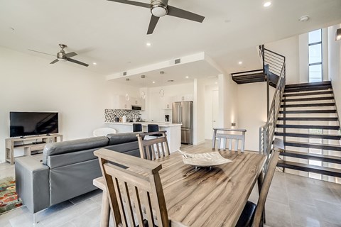 a living room with a wooden dining table and a staircase